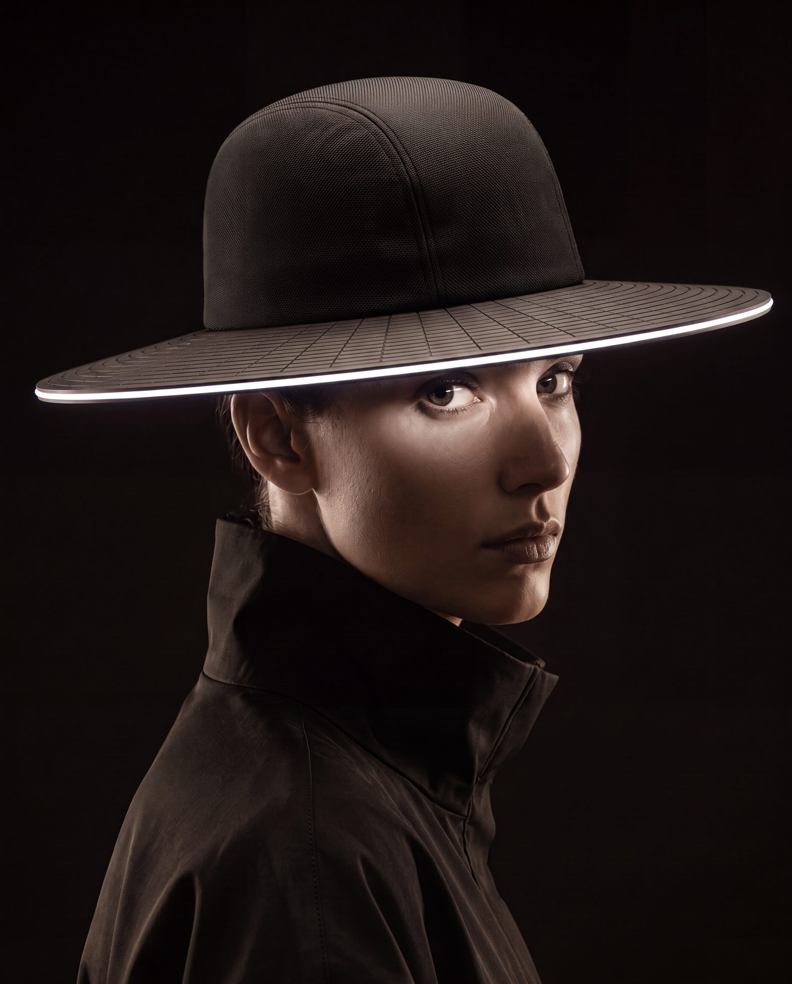 A woman in a dark coat wears SOLIS: a rounded knit crown and a wide flat brim with a thin line of light along its edge.